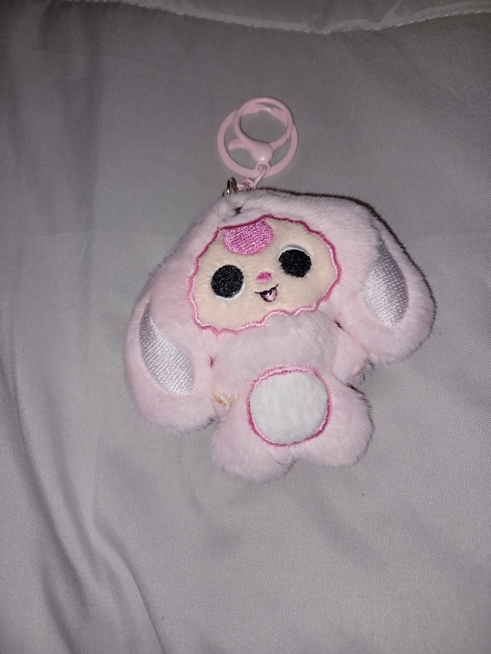 pink plush bunny keychain charm with black button eyes and a white belly patch